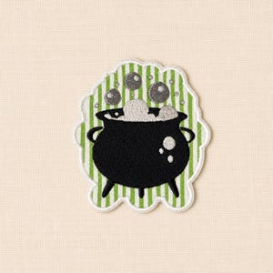 May include: An embroidered patch featuring a black three-legged cauldron with white bubbling liquid inside. The cauldron is set against a background of vertical light green and white stripes, with several grey bubbles floating above the rim.