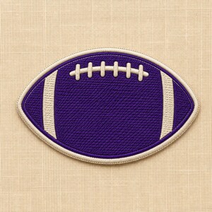 Puede incluir: Un parche bordado de forma ovalada con un diseño de balón de fútbol americano morado y detalles de costura en blanco. El parche tiene una superficie texturizada con un borde blanco prominente y rayas verticales blancas a cada lado del balón.