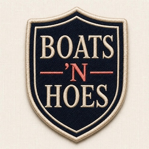 May include: A shield-shaped embroidered patch with a dark navy blue background and a beige border. The text BOATS and HOES is stitched in beige, while the letter N is stitched in red, flanked by two horizontal red lines in the centre.