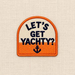 May include: An embroidered patch with a rounded top edge, featuring a cream-coloured upper section and an orange lower section. The text LET'S GET YACHTY? is stitched in dark blue, with a dark blue anchor icon centred below the text.