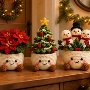 May include: Three crocheted holiday decorations in cream-colored pots with smiling faces and pink cheeks. The left pot holds a red poinsettia, the center pot a green Christmas tree with a yellow star, and the right pot three snowmen with red scarves.
