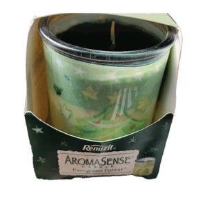 May include: A green glass candle in a cardboard box. The candle has a black wax top and is decorated with white stars and Christmas trees. The box has the text "Renuzit AromaSense Candle Evergreen Forest".