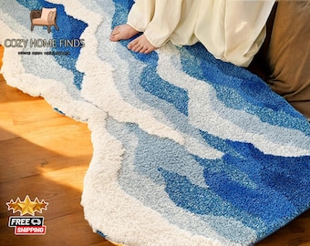 May include: A white and blue area rug with a wave pattern. The rug is made of soft, fluffy material and has a modern, abstract design.