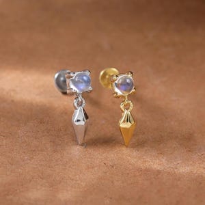 Örhänge i form av månsten med hänge i drakeform • Broskpiercing i sterlingsilver med ädelstenar • Helixlob med conch och tragus med platt baksida