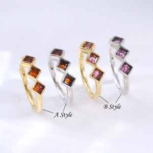May include: Four rings, each with three square gemstones. Two rings are gold-toned with brown gemstones, and two are silver-toned with either brown or pink gemstones. The rings are labelled "A Style" and "B Style".