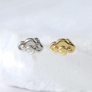 May include: A pair of cloud-shaped stud earrings. One earring is silver, the other gold. The earrings are small and have a minimalist design, suitable for everyday wear.
