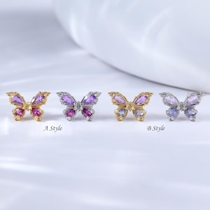 May include: Four butterfly-shaped earrings with colorful gemstones. Two pairs are labeled "A Style" and "B Style". The earrings feature gold and silver metal with pink, purple, and blue stones. The background is white.