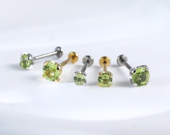 Könnte beinhalten: Fünf Nasenringe mit grünen Edelsteinen, mit goldenen und silbernen Stiften. Die Edelsteine sind quadratisch und haben einen leichten Gelbstich.