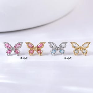 May include: Four butterfly-shaped jewelry pieces. The first is pink, the second is gold and pink, the third is silver and blue, and the fourth is gold and clear. The text "A Style" and "B Style" are below the jewelry.