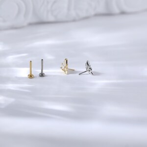 Puede incluir: Una colecci&oacute;n de cuatro piezas de joyer&iacute;a, que incluye dos tachuelas de espalda plana y dos pendientes decorativos. Una tachuela es dorada, la otra es plateada. Los pendientes presentan un dise&ntilde;o dorado y plateado.