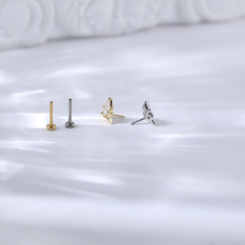 Puede incluir: Una colecci&oacute;n de cuatro piezas de joyer&iacute;a, que incluye dos tachuelas de espalda plana y dos pendientes decorativos. Una tachuela es dorada, la otra es plateada. Los pendientes presentan un dise&ntilde;o dorado y plateado.