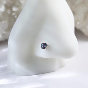 May include: A silver nose stud with a round, iridescent blue gemstone.