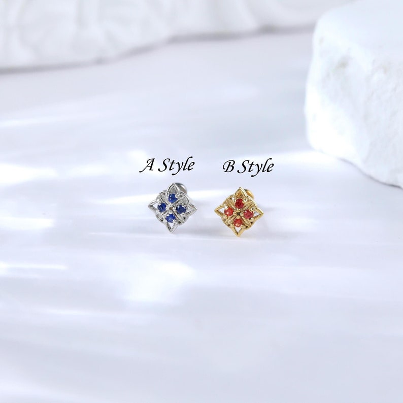 May include: Two styles of earrings with a square design. The first earring is silver with blue gemstones. The second earring is gold with red gemstones. The earrings are labeled "A Style" and "B Style".