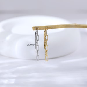 May include: Two chain earrings, one silver and one gold, are displayed against a soft, neutral background. The silver earring features a delicate, layered design, while the gold earring has a thicker chain. The earrings are approximately 29.5mm in length.
