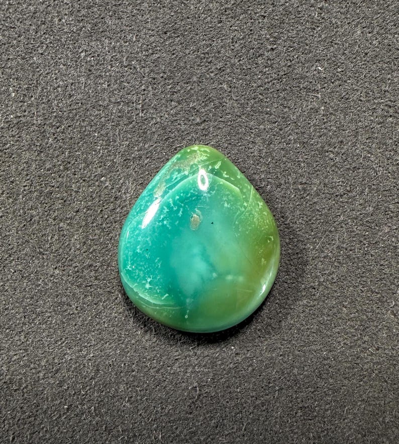 May include: A teardrop-shaped green and blue gemstone cabochon with a light green and white pattern.