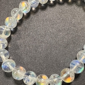 Pode incluir: Uma pulseira de contas de quartzo transparente. As contas redondas t&ecirc;m uma iridesc&ecirc;ncia interna semelhante ao arco-&iacute;ris. A pulseira &eacute; enfiada em um cord&atilde;o el&aacute;stico transparente. As contas t&ecirc;m aproximadamente 1,3 cm de di&acirc;metro.