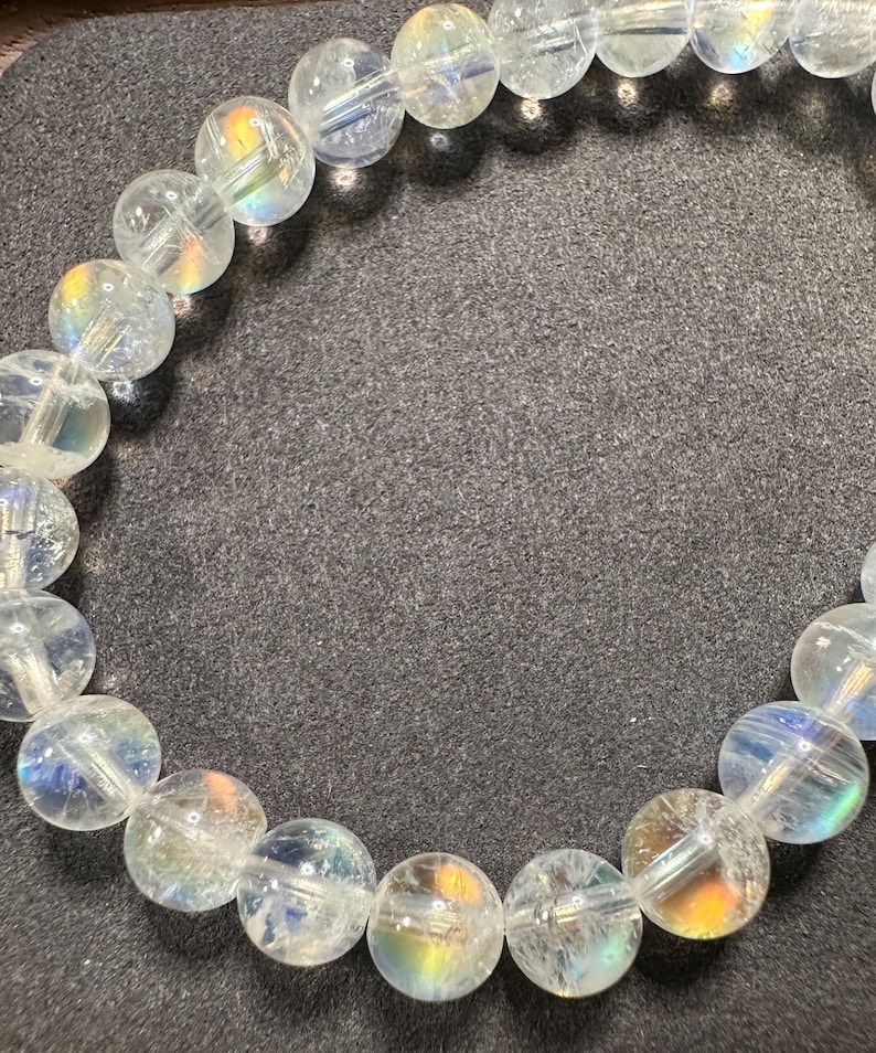 Pode incluir: Uma pulseira de contas de quartzo transparente. As contas redondas t&ecirc;m uma iridesc&ecirc;ncia interna semelhante ao arco-&iacute;ris. A pulseira &eacute; enfiada em um cord&atilde;o el&aacute;stico transparente. As contas t&ecirc;m aproximadamente 1,3 cm de di&acirc;metro.