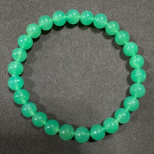 Puede incluir: Un brazalete de piedras preciosas verdes con cuentas redondas. El brazalete está hecho de piedras naturales y es un hermoso accesorio para cualquier ocasión.