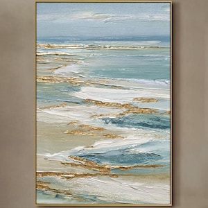 May include: Abstract ocean landscape painting with a gold frame. The artwork features textured brushstrokes in shades of blue, white, and gold, depicting waves and a horizon line. The painting is displayed on a neutral-colored wall.