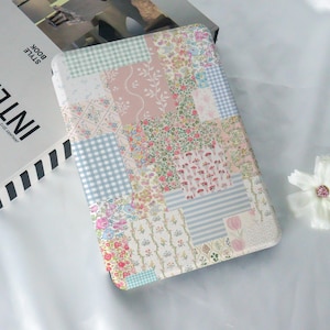 May include: A patchwork design iPad case with a variety of floral and geometric patterns in shades of pink, blue, and white.