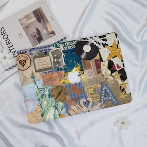 May include: A laptop case with a collage design. It features the Statue of Liberty, a vintage camera, a vinyl record, and the text "She believed she could so she did." The case has a checkered pattern and star accents.