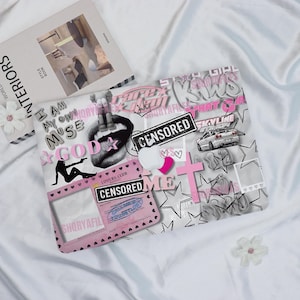 May include: A white laptop sleeve with a collage of graphics, including lips, stars, and the text "CENSORED." Pink and black accents are used throughout the design. A book titled "INTERIORS" is in the background.