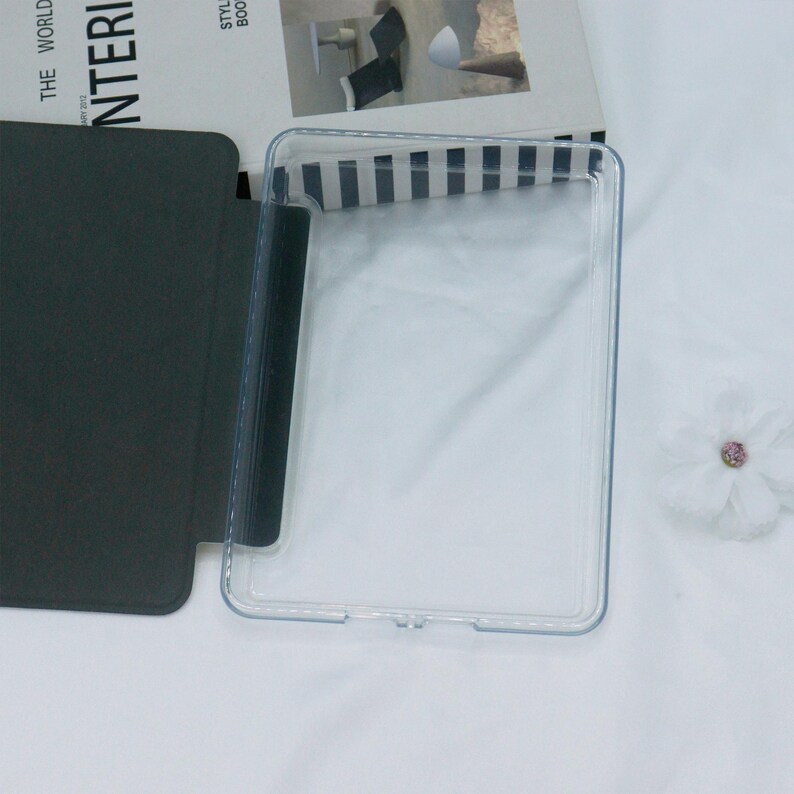 May include: A clear plastic case for a tablet or e-reader. The case has a black flap that folds over the front of the device.