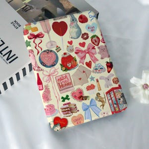 May include: A colorful digital tablet case with a vintage aesthetic. The case features a variety of images, including hearts, bows, candy, and animals. The text "Match Made in Heaven" and "Crazy 4 U" are visible on the case.
