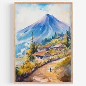 Könnte beinhalten: Aquarellmalerei einer Berglandschaft mit einem Dorf. Das Kunstwerk zeigt einen großen blauen Berg, eine kurvenreiche Straße und Häuser mit roten Dächern. Eine Person geht auf der Straße. Das Gemälde ist in einem hellbraunen Holzrahmen gerahmt.
