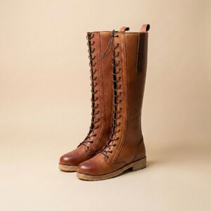 Peut inclure: Deux bottes hautes en cuir marron avec un design &agrave; lacets. Les bottes ont un style classique, d'inspiration &eacute;questre, avec un bout arrondi et une semelle robuste. Le cuir a une teinte riche et chaude. La hauteur des bottes est d'environ 40 cm.