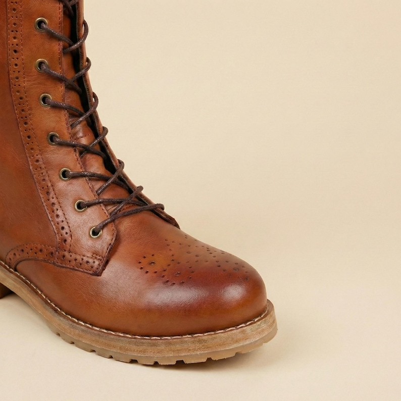Peut inclure: Gros plan sur une botte en cuir marron avec un design &agrave; lacets. La botte pr&eacute;sente des perforations d&eacute;coratives sur le bout et une semelle robuste de couleur claire. Les lacets sont de couleur marron fonc&eacute;.