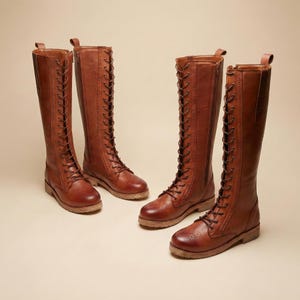 Peut inclure: Quatre paires de bottes hautes en cuir marron avec des lacets sur le devant et des d&eacute;tails ajour&eacute;s. Les bottes ont un design classique, avec une tige haute et une semelle robuste. Les bottes sont dispos&eacute;es dans un studio avec un fond neutre.