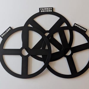 May include: Three black plastic golf putting practice aids with labels: "Rollers", "Fairway Drivers", and "Approach".
