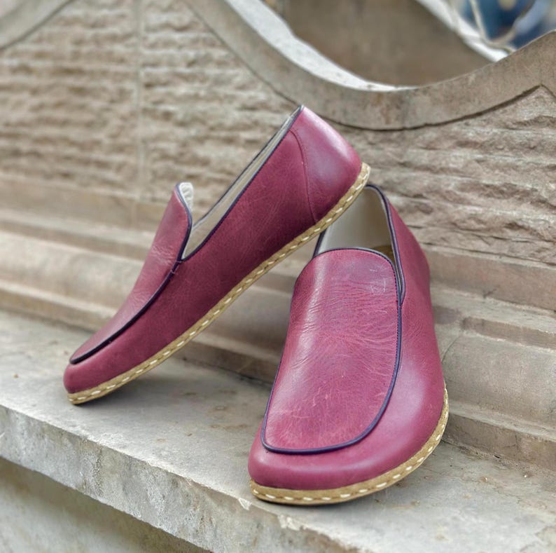 Puede incluir: Un par de zapatos de cuero burdeos de vestir sin cordones con suela cosida de color marr&oacute;n claro.