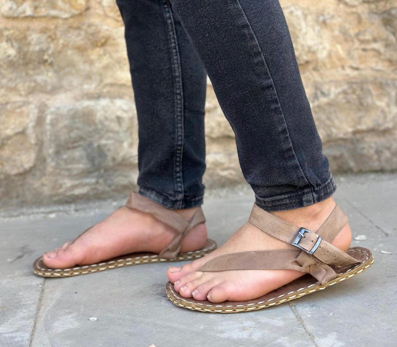 Puede incluir: Un par de sandalias de cuero marr&oacute;n con una hebilla y un borde cosido. Las sandalias tienen un dise&ntilde;o sencillo y est&aacute;n hechas de cuero de alta calidad.
