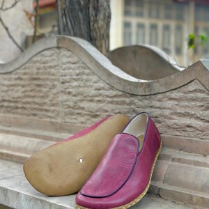 Puede incluir: Un par de zapatos de cuero burdeos de vestir sin cordones con un borde cosido y una suela marr&oacute;n claro.