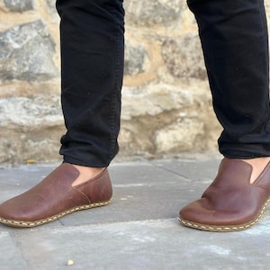 K&ouml;nnte beinhalten: Braune Lederschuhe zum Hineinschl&uuml;pfen mit wei&szlig;en N&auml;hten an der Sohle.