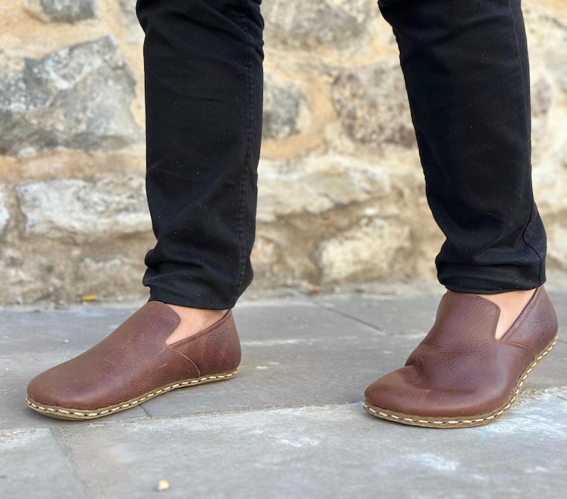 K&ouml;nnte beinhalten: Braune Lederschuhe zum Hineinschl&uuml;pfen mit wei&szlig;en N&auml;hten an der Sohle.