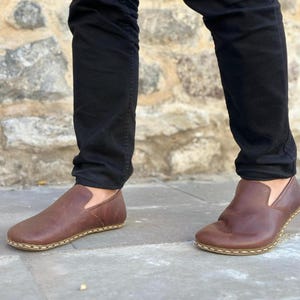 K&ouml;nnte beinhalten: Braune Lederschuhe zum Hineinschl&uuml;pfen mit gen&auml;htem Rand und Gummisohle.