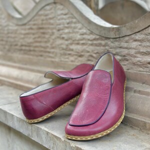 Puede incluir: Un par de zapatos de cuero burdeos de vestir sin cordones con suela cosida marr&oacute;n.