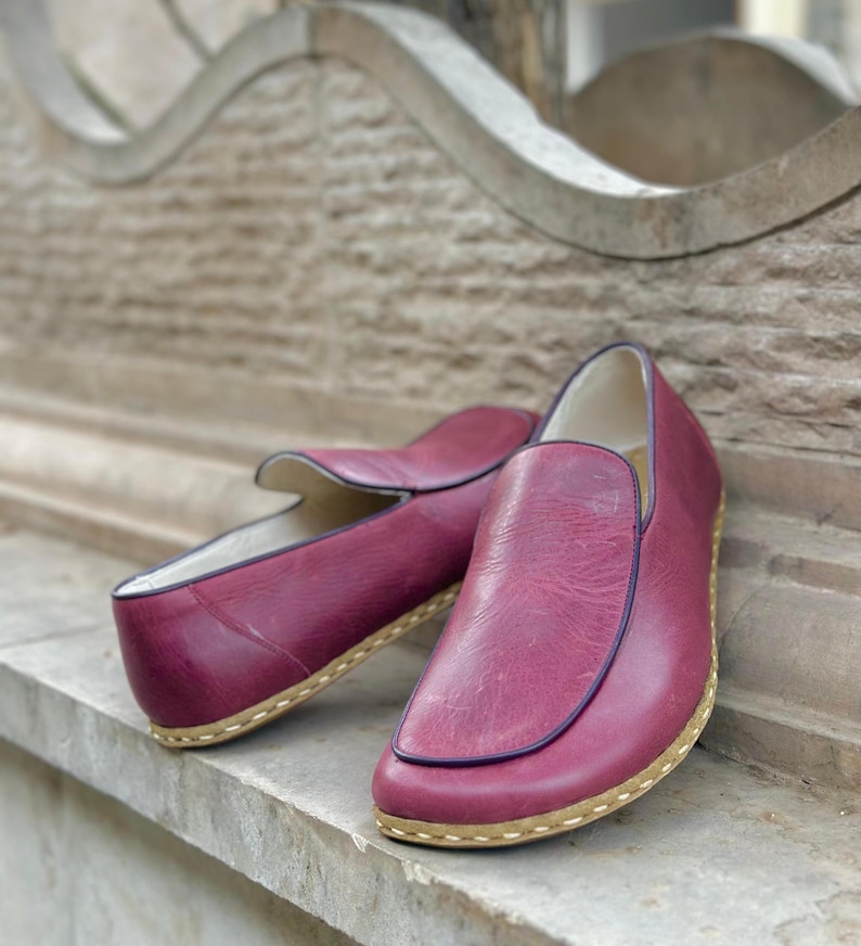 Puede incluir: Un par de zapatos de cuero burdeos de vestir sin cordones con suela cosida marr&oacute;n.