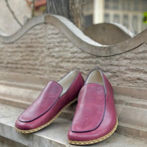 Puede incluir: Un par de zapatos de cuero burdeos con suela cosida de color marr&oacute;n claro.