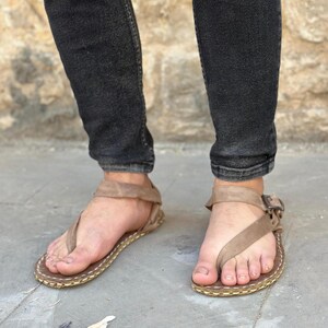 Puede incluir: Un par de sandalias de cuero marr&oacute;n con cierre de hebilla. Las sandalias tienen un dise&ntilde;o sencillo y est&aacute;n hechas de un material suave y c&oacute;modo.