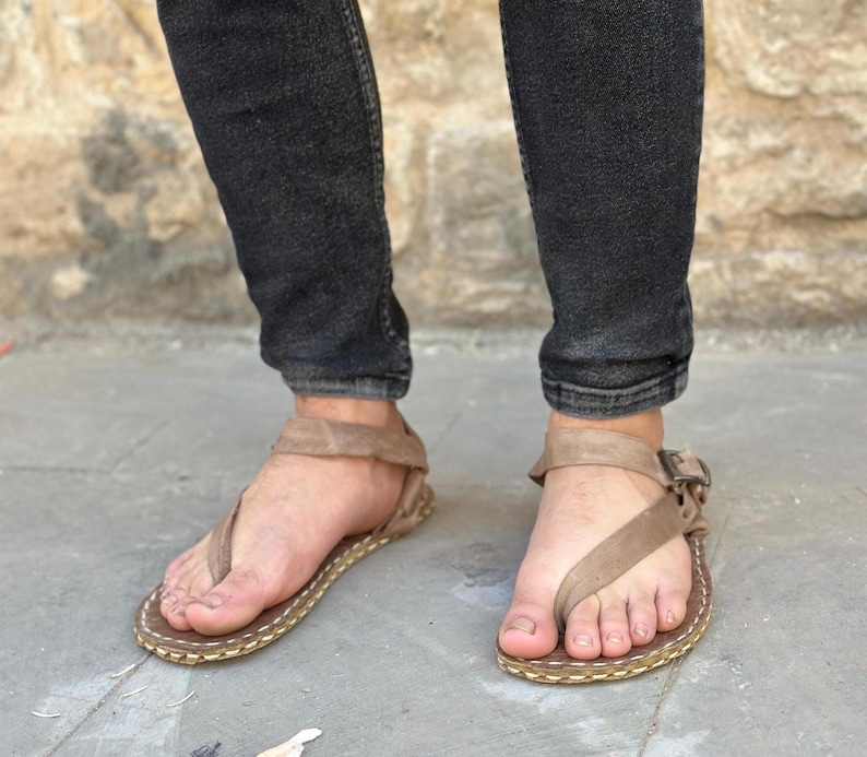 Puede incluir: Un par de sandalias de cuero marr&oacute;n con cierre de hebilla. Las sandalias tienen un dise&ntilde;o sencillo y est&aacute;n hechas de un material suave y c&oacute;modo.