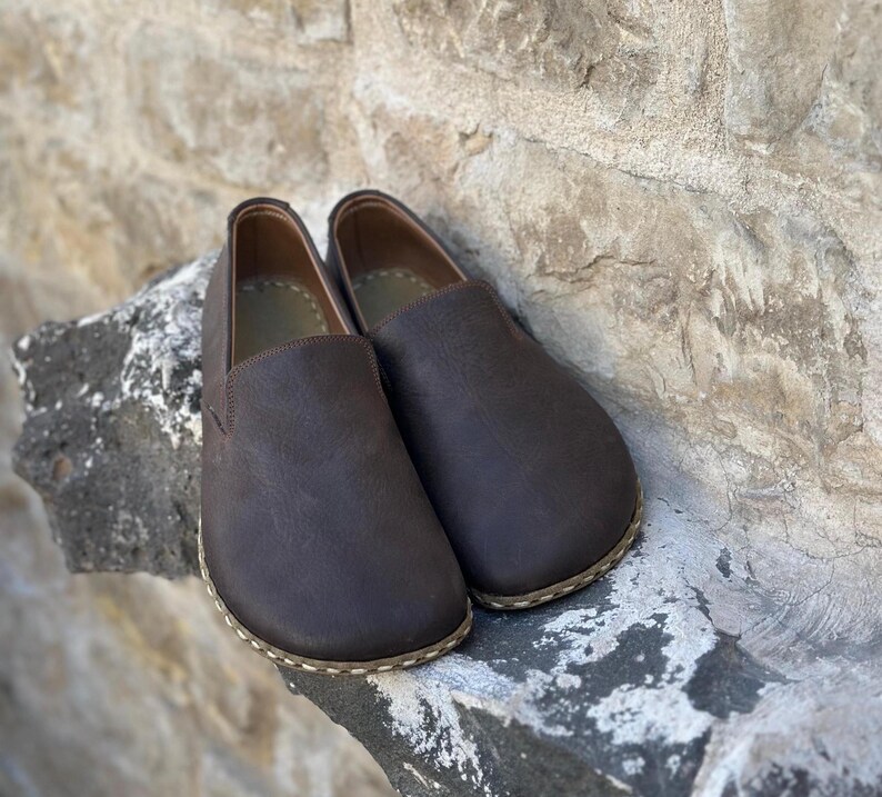 May include: A pair of brown leather slip-on shoes with a stitched edge.