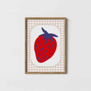May include: A framed art print featuring a stylized strawberry illustration. The strawberry is red with blue seeds and a blue stem, set against a white scalloped border. The background has a grid pattern in a light brown color.