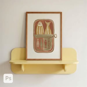 May include: A framed art print depicting sardines in a can, with a brown wooden frame. The artwork features a salmon-colored can with several fish illustrations in shades of white, yellow, and brown. The print is displayed on a yellow shelf.