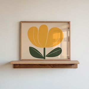 Pode incluir: Uma impressão emoldurada de uma flor amarela estilizada com folhas verdes sobre um fundo creme. A moldura é de madeira e tem um acabamento natural.