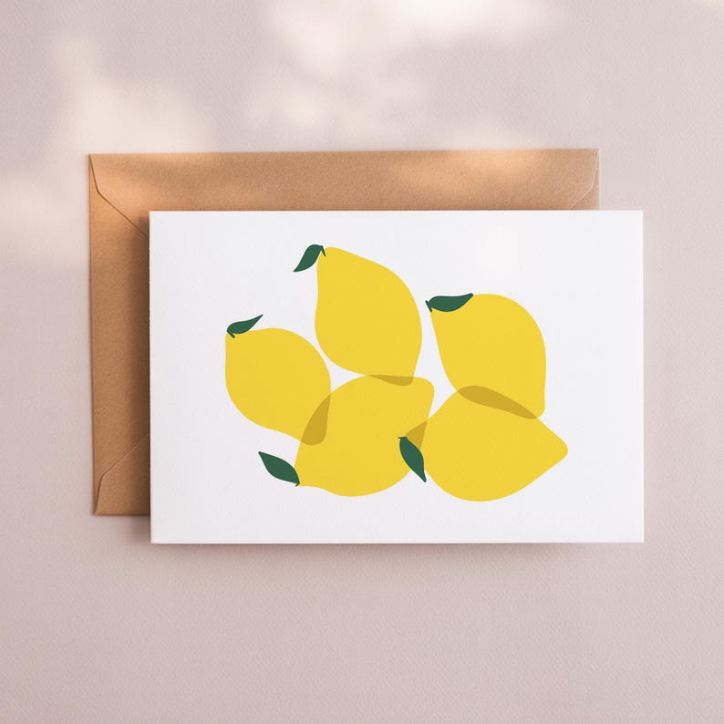 May include: Greeting card featuring a yellow lemon illustration with green leaves on a white background. The card is paired with a brown envelope, suitable for sending a note or message.