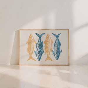 May include: A framed art print featuring four stylized fish in a row. Two fish are a golden yellow color, and two are a deep blue. The fish are arranged on a cream-colored background, with a natural wood frame.